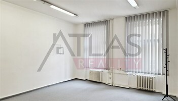 Světlá kancelář s kobercem a velkými okny, moderní žaluzie, bílé stěny, ideální pro firemní prostory.