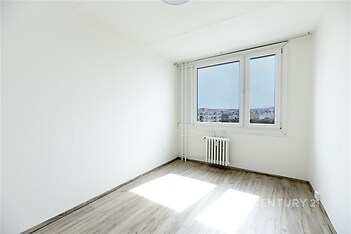 Světlý pokoj, moderní podlahy s dřevěným vzhledem, velká okna s výhledem, minimalistický styl.