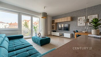 Světlý obývací pokoj s velkými okny, moderní parketovou podlahou a stylovým nábytkem.