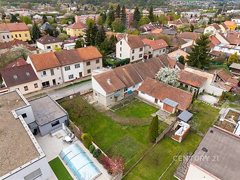 Prostorná zahrada s travnatou plochou a terasou, obklopená rodinnými domy, ve vilové čtvrti.