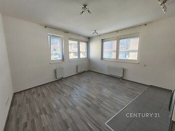 Světlý obývací pokoj s velkými okny, moderní plovoucí podlahou a centrálním vytápěním, ideální pro komfortní bydlení.