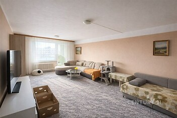 Prostorný obývací pokoj se světlým koberce, velkými okny a útulným nábytkem, nabízí světlý interiér s moderním designem.