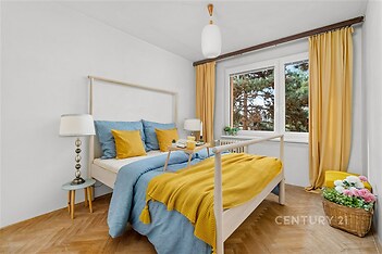 Světlá ložnice, parketová podlaha, velká okna, moderní interiér, prostorné uspořádání, světlé dekorace, výhled do zeleně.