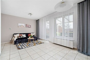 Světlý obývací pokoj s dlažbou, velkými okny a moderním vybavením, ideální pro rodinný život.