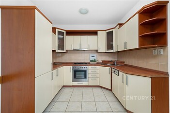 Moderní kuchyň s dlažbou, dřevěnými deskami a vestavěnými spotřebiči, ideální pro rodinné vaření a společenské setkání.