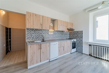 Moderní kuchyň s dřevěnou linkou, parketová podlaha, velké okno zajišťující světlost, mozaikový obklad stěny pro stylový vzhled.