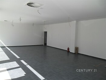Světlý obývací prostor s dlažbou, velkými okny a moderními stropními rozvody, ideální pro otevřený design interiéru