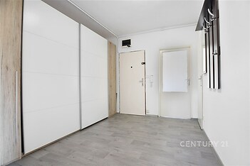 Chodba s moderními dveřmi, světlou parketovou podlahou a vestavěnými skříněmi nabízí praktický a elegantní vstupní prostor.