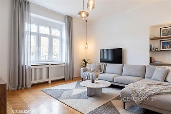 Světlý obývací pokoj s parketovou podlahou, moderní sedací soupravou a velkými okny, které zajišťují dostatek přirozeného světla.