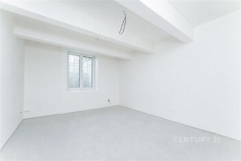 Prázdná místnost s bílými stěnami, betonová podlaha, velké okno, moderní rekonstrukce, minimalistický design.