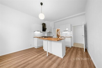 Moderní kuchyň s dřevěnou podlahou, bílými skříněmi a ostrůvkem, světlá místnost pro pohodlné vaření a stolování.