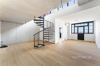 Prostorný obývací pokoj s dubovou parketovou podlahou, moderní točité schodiště a velká okna poskytující dostatek přirozeného světla