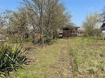 Zahrada s ovocnými stromy a travnatou plochou, vhodná pro rekreační využití, nabízí klidné prostředí a potenciál k rozvoji.