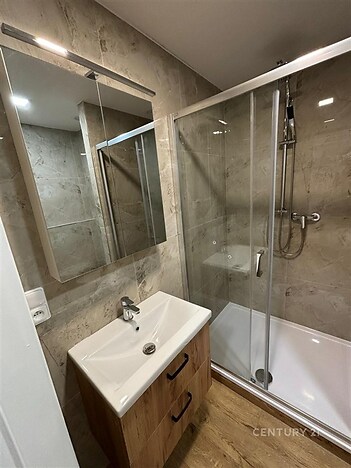 Koupelna s moderním sprchovým koutem, parketovou podlahou a světlými keramickými obklady, elegantní dřevěná skříňka pod umyvadlem