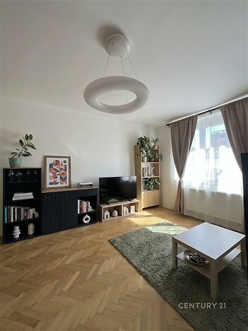 Světlý obývací pokoj s parketovou podlahou.