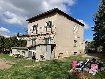 Dvoupatrový dům s balkonem, zahrada s neudržovaným trávníkem, potřeba rekonstrukce, částečně dřevěná fasáda, klidná lokalita.