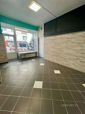 Komerční prostor s dlažbou, velkými okny a moderním vzhledem, ideální pro podnikání nebo kancelářské využití.