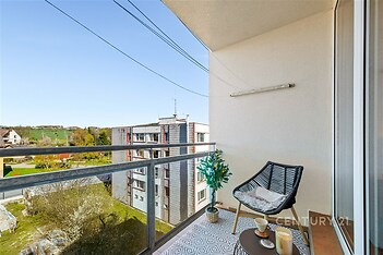 Balkón s moderní keramickou dlažbou, výhledem na okolní zeleň a pohodlným venkovním posezením, vhodný pro relaxaci.