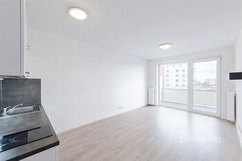 Světlý obývací pokoj s moderní parketovou podlahou, velká okna a světlá výmalba dodávají prostoru vzdušnost a příjemnou atmosféru.