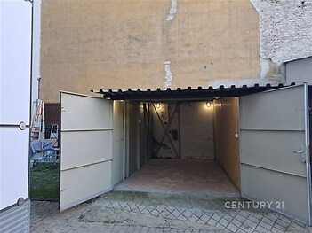 Prázdná garáž s dřevěnou podlahou a betonovými stěnami, jednoduchá konstrukce, vhodná pro parkování nebo uskladnění věcí.