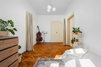 Světlá ložnice s parketovou podlahou a bílými zdmi, vybavená vestavěnými skříněmi a dekorovaná zelenými rostlinami, moderní a prostorná