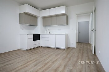 Moderní kuchyň s parketovou podlahou, světlé skříňky a vestavěné spotřebiče v nově rekonstruovaném bytě.