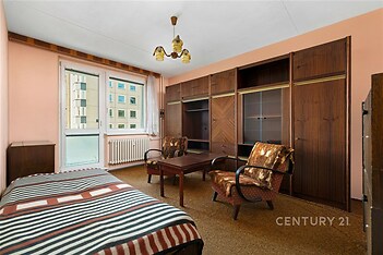 Prostorná ložnice s dřevěným nábytkem, vestavěné skříně a balkon. Kobercová podlaha, retro styl, ideální pro rekonstrukci.