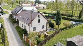 Velký rodinný dům s moderní fasádou a šikmou střechou nabízí prostornou zahradu s bazénem, nachází se v klidné a zelené lokalitě.