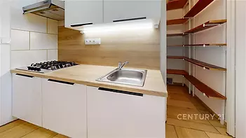 Moderní kuchyň s dřevěnou pracovní deskou, vestavěnou spíží a světlou dlažbou, ideální pro efektivní vaření a ukládání potravin.