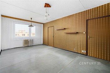 Prázdný obývací pokoj s betonovou podlahou, dřevěné panely, velké okno, minimalistický design, světlý prostor, připraven k rekonstrukci