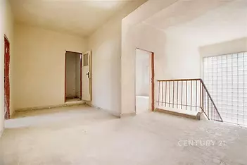 Světlá chodba s dlažbou, velká okna poskytující přirozené světlo, moderní styl a světlé zdi vytvářející prostorný dojem.