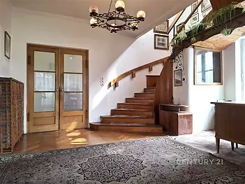 Prostorná předsíň s parketovou podlahou a dřevěným schodištěm, velká okna umožňují dostatek světla, klasický styl interiéru