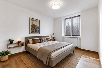 Prostorná ložnice s parketovou podlahou, velkými okny a moderním designem.
