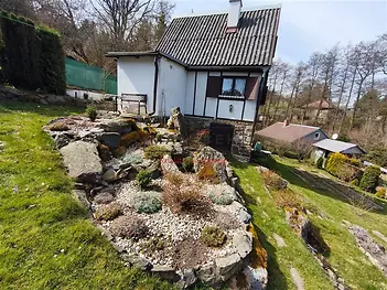 Kompaktní venkovský dům s kamennými prvky a zahradní skalka. Umístěný v malebné krajině, ideální pro rekreaci.