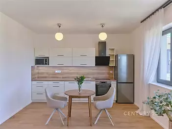 Moderní kuchyň s dřevěnou podlahou, světlým nábytkem a velkými okny, elegantní povrchová úprava, prostorný design, vynikající světelnost.