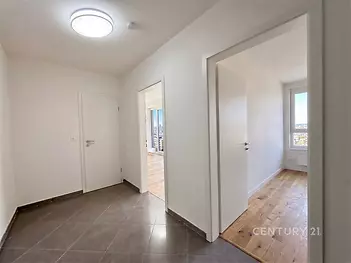 Chodba s dlažbou, moderní styl, propojená s pokoji s parketovou podlahou, světlý interiér, bílá výmalba, velká okna v pozadí