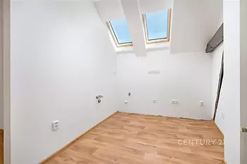 Světlá podkrovní místnost, dřevěná podlaha, střešní okna, moderní interiér, připravená k dokončení, energeticky úsporné prvky.