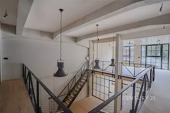 Útulné schodiště s dřevěnými schody, moderní kovové zábradlí a velká okna, kombinace industriálního a moderního stylu, světlý interiér.