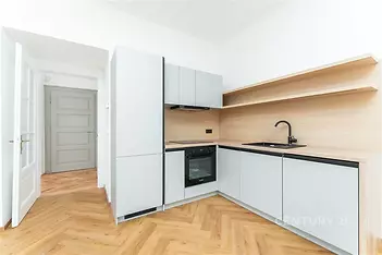Moderní kuchyň s parketovou podlahou, vestavěnými spotřebiči a světlými dřevěnými povrchy, nabízí elegantní a praktický design.