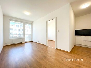 Světlý obývací pokoj, parketová podlaha, moderní design, velká okna, přístup na balkon, propojený s kuchyňským koutem.