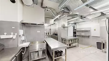 Průmyslová kuchyň s nerezovým vybavením, keramickou dlažbou a moderními ventilačními systémy, ideální pro gastronomické provozy