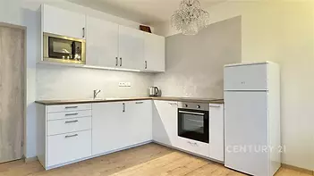 Moderní kuchyň s parketovou podlahou, vestavěnými spotřebiči a světlým interiérem, stylový design a funkční uspořádání