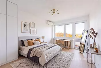 Prostorná ložnice s parketovou podlahou, vestavěné skříně a moderní nábytek. Velká okna zajišťují dostatek světla a výhled na balkon.