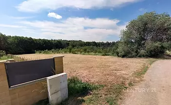 Přírodní pozemek obklopený zelení, vhodný pro stavbu nebo rekreaci, nabízí klidné prostředí a snadný přístup po zpevněné cestě.