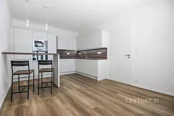 kuchyně s backsplash, ploché panelové skříňky, mikrovlnná trouba, dřevěná podlaha, a bílé skříně