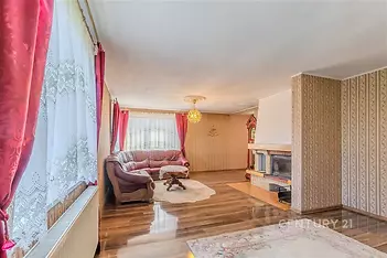 Světlý obývací pokoj s parketovou podlahou, velkými okny a krbovými kamny, klasický styl, prostorný a útulný interiér.
