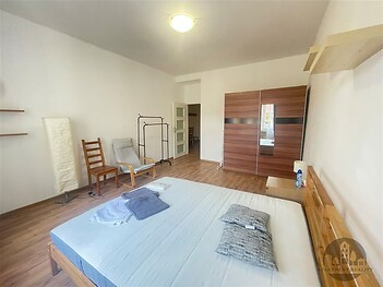 Prostorná ložnice s parketovou podlahou, moderní vestavěné skříně a světlé stěny vytvářejí příjemnou atmosféru pro relaxaci.