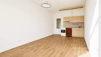 Světlá kuchyňská linka s dřevěnou podlahou, moderním designem a velkými okny poskytujícími přirozené světlo