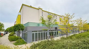 Moderní komerční prostor s prosklenou fasádou a upraveným okolím, ideální pro podnikání v klidné lokalitě s dobrou dostupností.