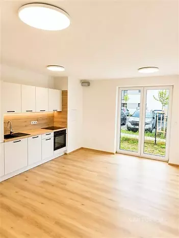 Světlý obývací pokoj s moderní kuchyní, parketová podlaha a velká okna poskytují elegantní a prostorný pocit v nově zrekonstruovaném interiéru.